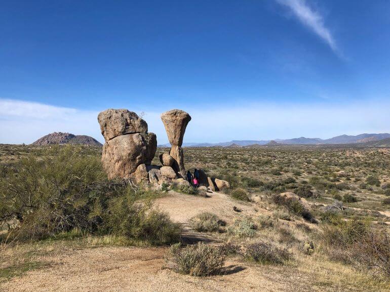 Hikers climbing rocks atop a hill on the Marcus Landslide Trail in the McDowell Sonoran Preserve in Scottsdale, Arizona