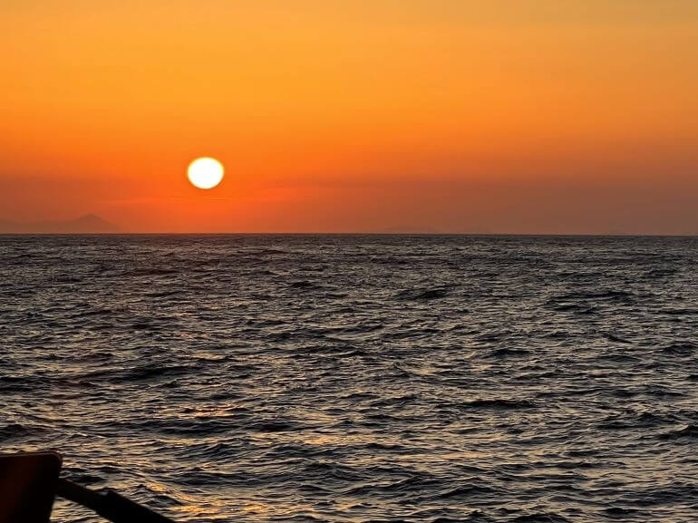 Sunset seen from a catamaran in the waters below Oia, Crete, Greece