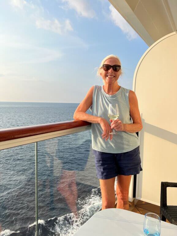 Catherine Sweeney with a glass of wine on the veranda of her Viking Sea stateroom