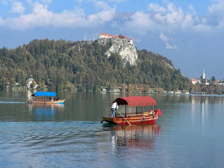 Pletna boats on Lake Bled in Slovenia with Bled Castle in on a hilltop above the lake