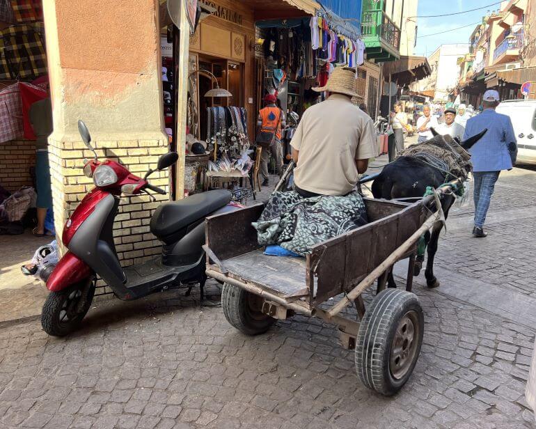 Donkey cart going down narrow lane in Marrakech medina and motorbike parked on the side