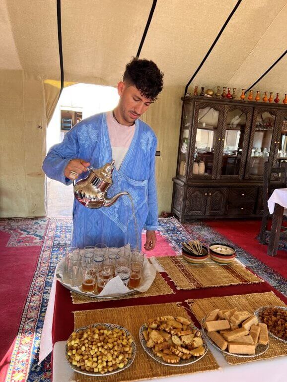 Mint tea being poured in the dining tent of a luxury desert camp in the Sahara on a Collette guided tour, Morocco